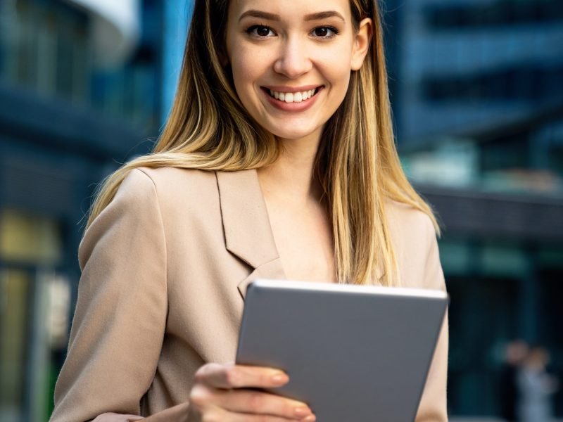 successful-businesswoman-using-a-digital-tablet-while-standing-in-front-of-business-building.jpg